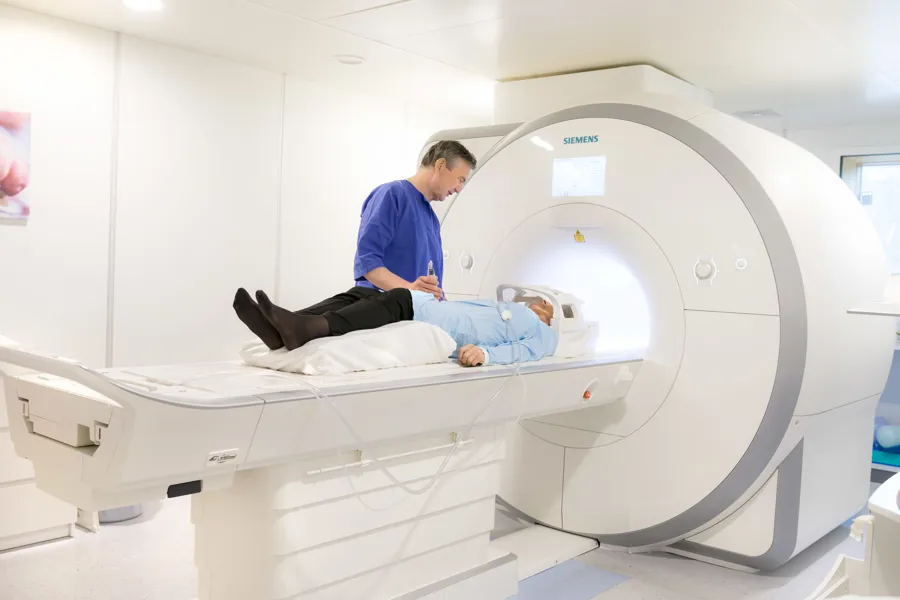 En pasient liggende i en MR maskin som får instrukser fra en radiograf