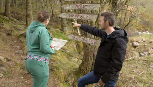 To personer på tur i skogen, en viser vei