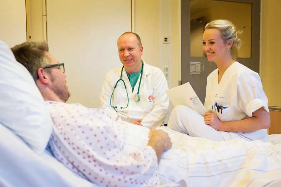 En lege  og en sykepleier som snakker med en pasient