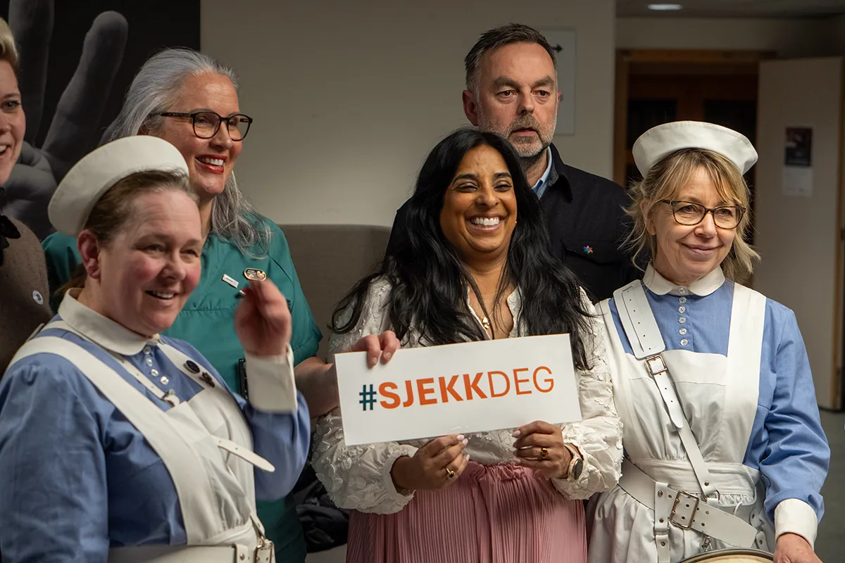 En gruppe mennesker, sykepleiere og kultur- og likestillingsminister Lubna Jaffery som holder et skilt med #sjekkdeg