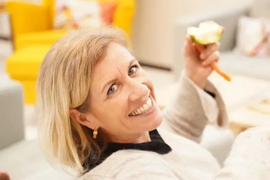 En smilende dame som spiser et eple