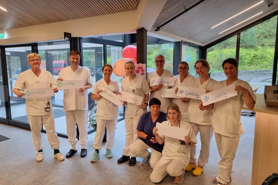 En gruppe mennesker som holder et skilt med tekst #sjekk deg