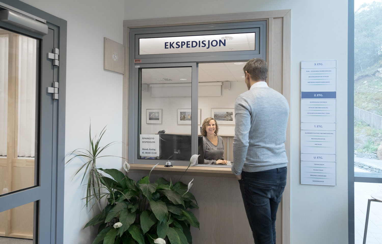 En smilende resepsjonist snakker med en pasient på Betanien DPS. Foto: Nils Olav Mevatne.