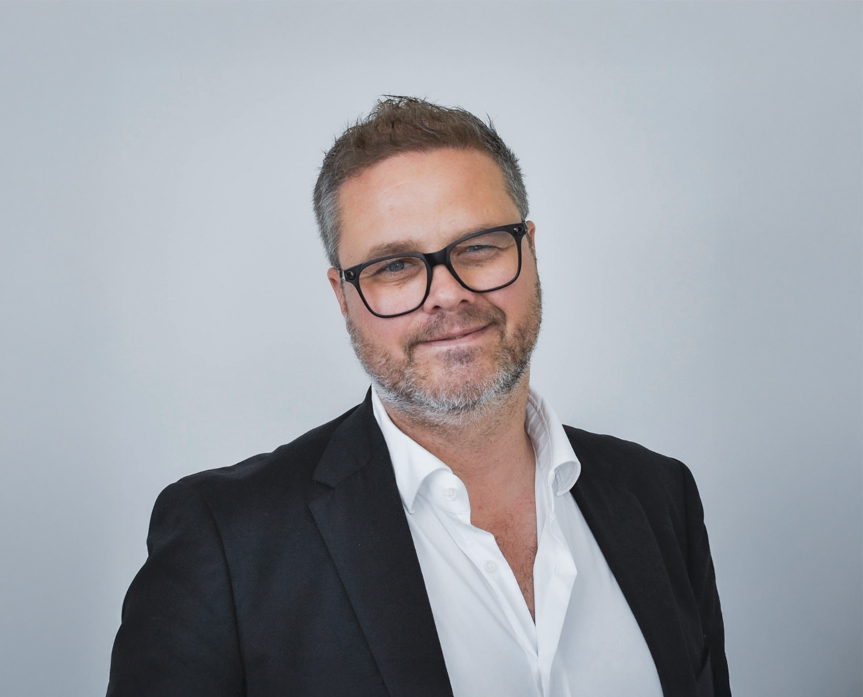 Portrett av Lars-Petter, iført briller, dressjakke og hvit skjorte.