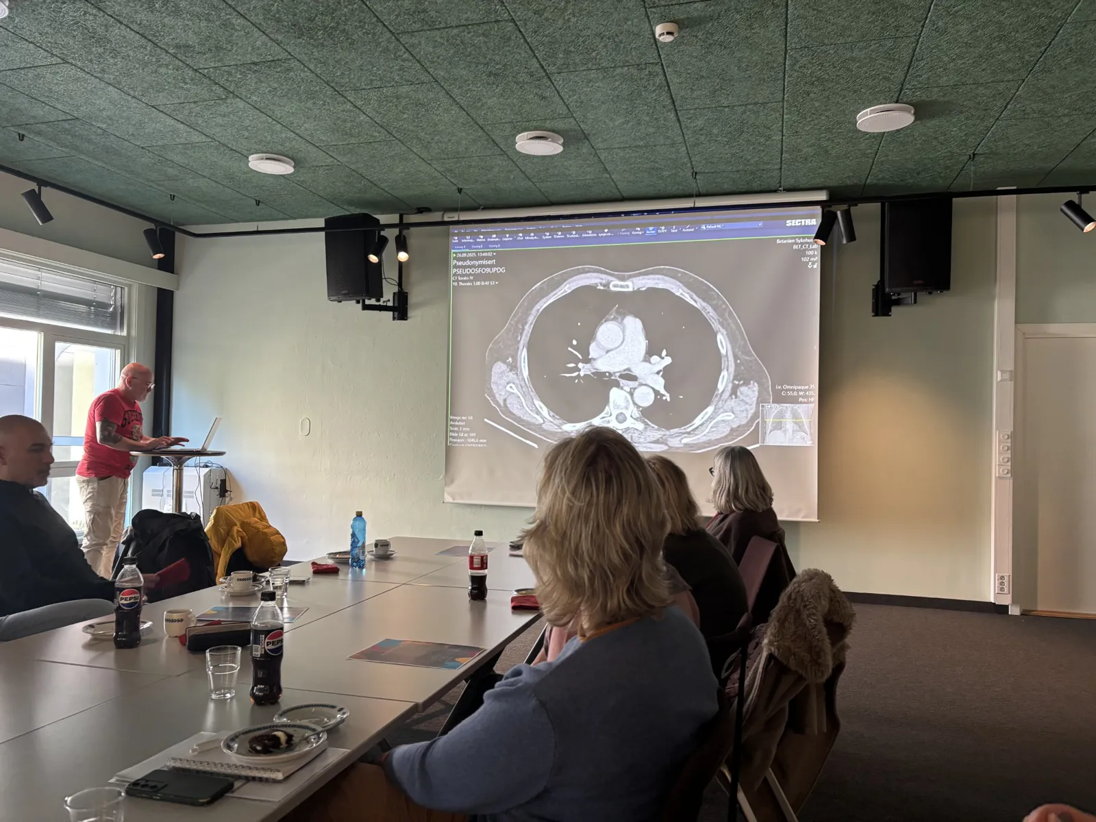 En gruppe mennesker som sitter ved et bord og ser på et projisert bilde